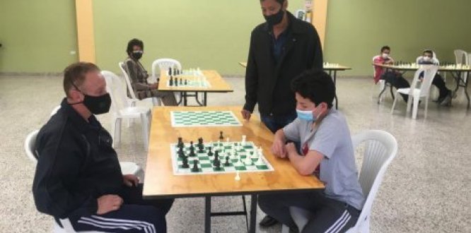 Profesor enseñando a juagar ajedrez a niño y adulto mayor